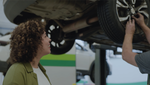 mulher-cacheada-analiza-mecaninco-colocando-parafuso-em-roda