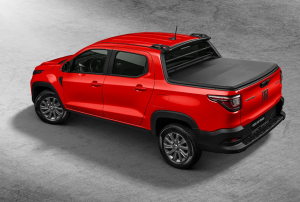 Fiat Strada vermelha cabine dupla vista de perfil, com quatro portas e caçamba, estacionada em ambiente urbano.