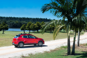 Fiat Argo estacionado em estrada de areia à beira da praia, com o mar ao fundo e clima ensolarado."