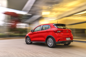 Fiat Argo vermelho HGT em movimento, visto de frente, sobre piso liso e iluminado, como em estúdio ou salão