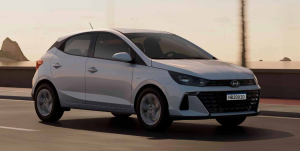 Hyundai HB20 Sense Plus cinza em movimento em uma avenida urbana, com destaque para o design frontal e luzes acesas.