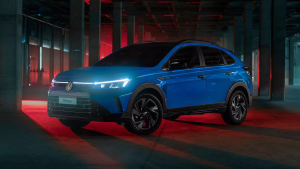 Volkswagen Nivus azul visto de perfil, estacionado em área externa, destacando o design de cupê e rodas de liga leve.