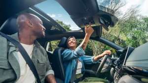 duas pessoas sentadas no interior de um Volkswagen T-Cross, sorrindo e interagindo, com destaque para o painel e acabamento do veículo.
