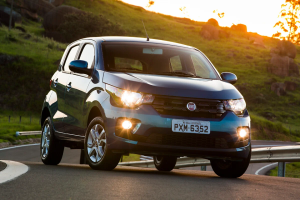 Fiat Mobi azul rodando na estrada ao fim do dia, hatch compacto em destaque com luz do entardecer