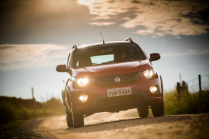 Fiat Mobi vermelho circulando em uma estrada de terra, destacando seu visual compacto e versátil em ambiente fora do asfalto.