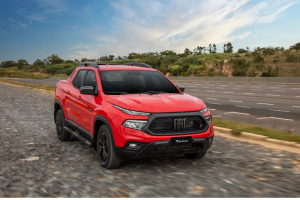 Fiat Toro vermelha em movimento na estrada, com destaque para o design robusto e perfil aerodinâmico da picape.