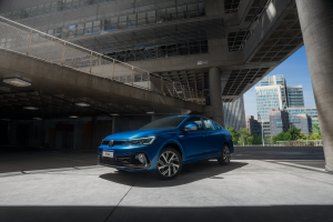 Volkswagen Virtus azul estacionado em ambiente de cimento, com fundo minimalista e tons acinzentados destacando o design do sedã.