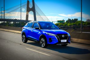 Nissan Kicks azul em movimento na estrada, com foco na dirigibilidade e estabilidade do SUV.