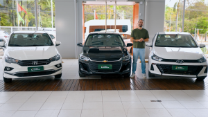 Carros Onix Plus, HB20S e Cronos estacionados em loja Seminovos virados para a frente.