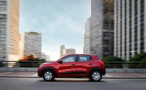 Renault Kwid vermelho em movimento visto de perfil, destacando o design compacto e urbano do subcompacto.