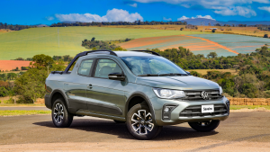 Volkswagen Saveiro 2023 na cor cinza, estacionada em um ambiente rural, cercada por árvores e vegetação típica do interior.