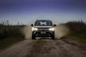 Volkswagen Taos visto de frente em uma estrada de terra, com poeira levantada em movimento.