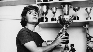 Maria Teresa de Filippis segurando um troféu após uma corrida, simbolizando sua conquista como a primeira mulher a competir na Fórmula 1.