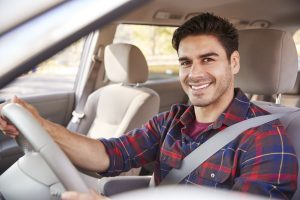 Young man in car driving seat looking to camera, portrait