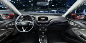 interior de um Chevrolet Onix com foco no painel central e volante, tela multimídia acesa exibindo o sistema Uconnect