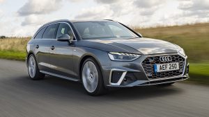 Audi A4 na cor cinza em movimento. Estrada com área verde na lateral.