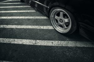 Modern rims on wheel of black car at asphalt road