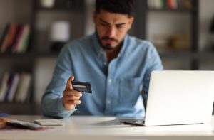 Man, hands and laptop with credit card for online shopping, ecommerce or wireless transaction on desk. Hand of male on computer for internet banking, app or financial purchase or payment on table
