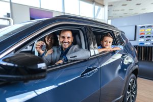 happy-family-celebrating-new-car-purchase-at-dealership