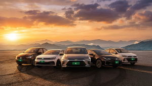 Cinco carros sedãs enfileirados e centralizados, da esquerda para a direita nas cores preto, branco, prata, preto e branco.