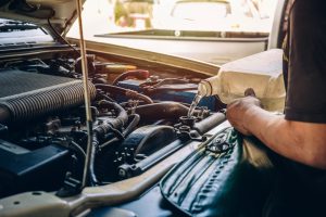 maleprofessionalmechanicpouringantifreezecoolantliquidintocarengine