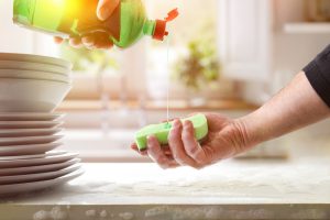 Detergente, pessoa lavando vasilha com as mãos com espuma.