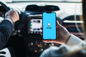 girlinsidecarholdingsmartphonewithwazeapponscreen
