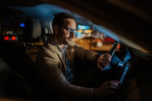 motorista, tecnologia, equipamentos. Calm,Businessman,Driving,Alone,At,Night,,Adjusting,Car,Stereo,During