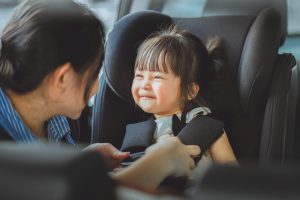 alovingasianmothercarefullybuckleshersmilingtoddlerdaughter