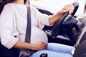 closeupoffastenpregnantwomanatwheeldrivingcar
