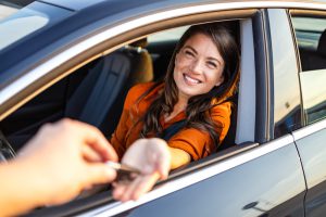Mulher recebe a chave do carro, motorista