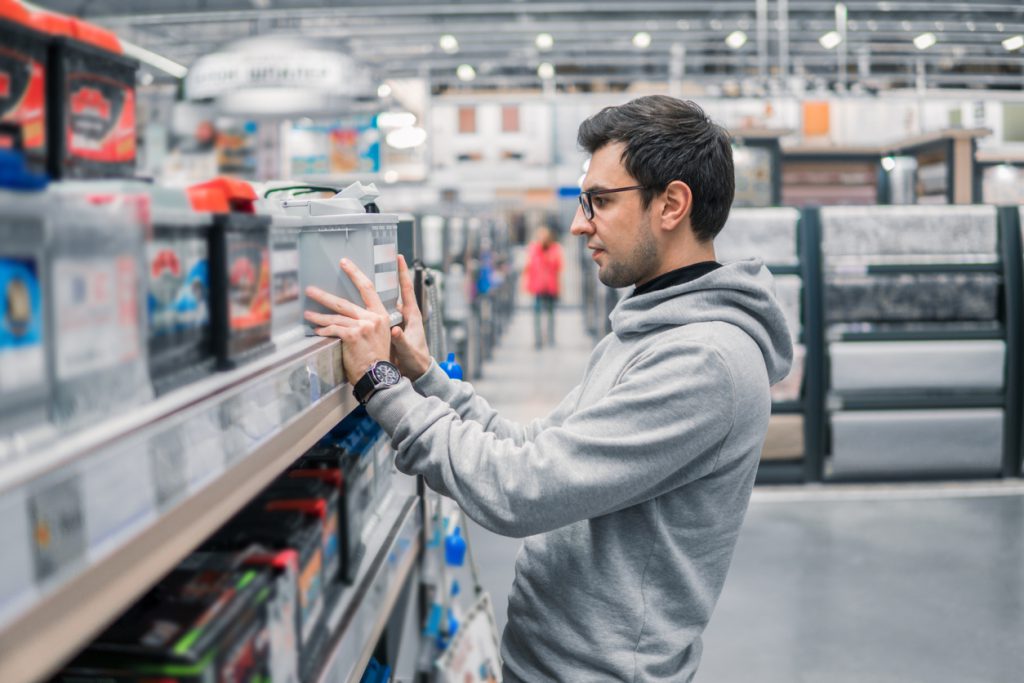 Homem comprando bateria de carro no supermercado