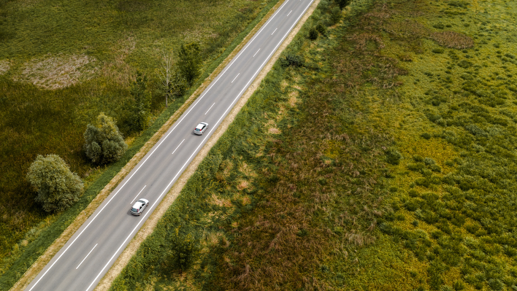 Dois carros são vistos em estrada plana.