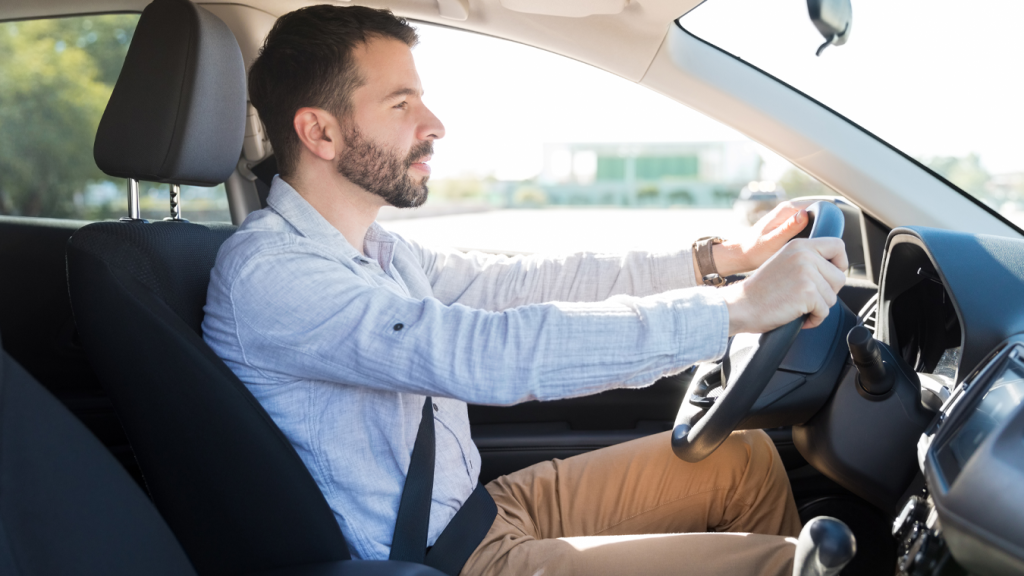 Motorista é visto com as duas mãos no volante, atento ao trânsito, seguindo as orientações da direção defensiva.