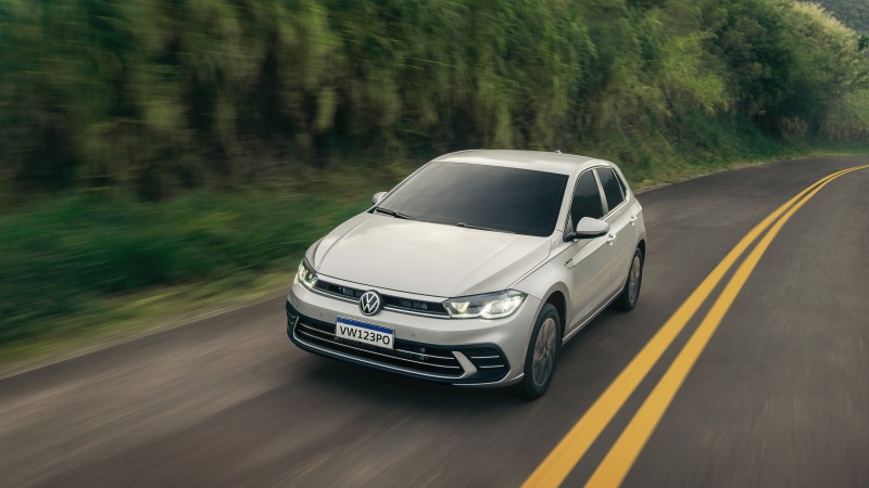 Volkswagen Polo cinza em movimento na estrada, com destaque para o design frontal e os contornos aerodinâmicos do modelo.