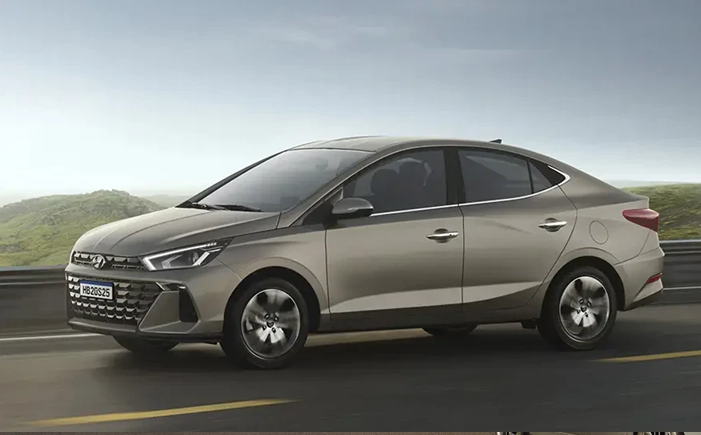 Hyundai HB20S cinza em movimento na estrada, com paisagem ao fundo