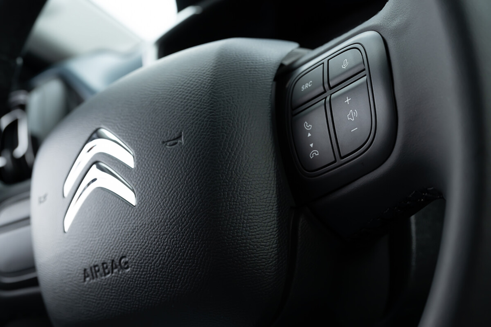 Volante do Citroën C3 com comandos multifuncionais e detalhes de acabamento em destaque.