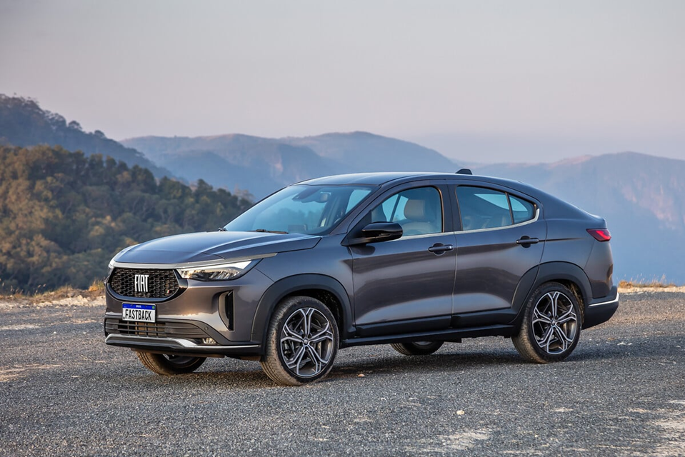 Fiat Fastback cinza estacionado em cenário com montanhas ao fundo, destacando o design esportivo do modelo.
