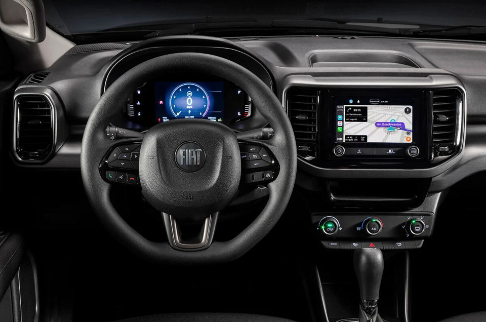 Detalhe do volante e painel da Fiat Toro, com destaque para o acabamento interno e a central multimídia iluminada.