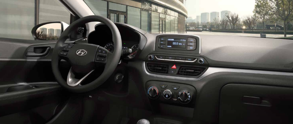 Painel do Hyundai HB20 Sense com acabamento em tons escuros, volante multifuncional e central multimídia em destaque.