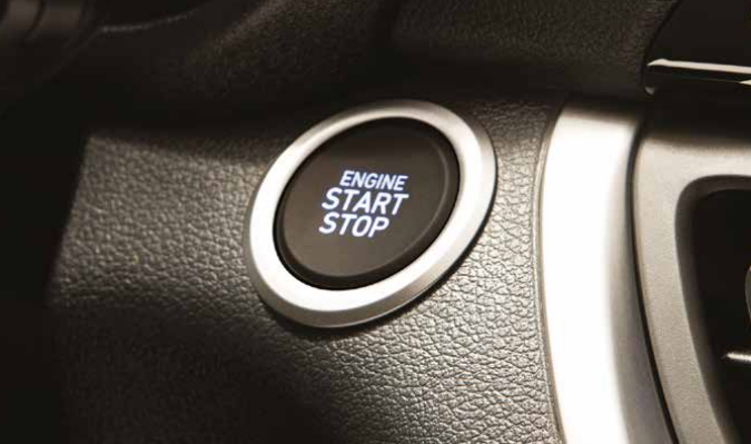 Detalhe do botão Start Stop iluminado no interior de um carro, com foco no acabamento ao redor e painel parcialmente visível. Perguntar ao ChatGPT