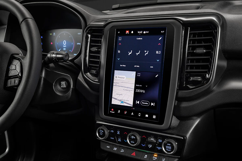 Central multimídia da Fiat Toro em destaque, mostrando a tela iluminada com comandos de conectividade e acabamento do painel ao redor.