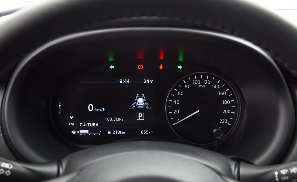 Painel do Nissan Kicks com foco no computador de bordo iluminado, exibindo informações digitais de condução e consumo.