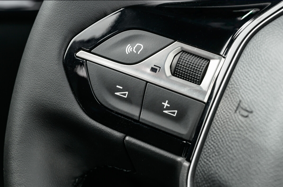 Detalhe do volante do Peugeot 208 com botões de controle integrados para multimídia e funções do computador de bordo.