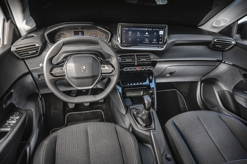 Painel do Peugeot 208 com volante multifuncional, detalhes digitais iluminados e acabamento moderno em destaque.