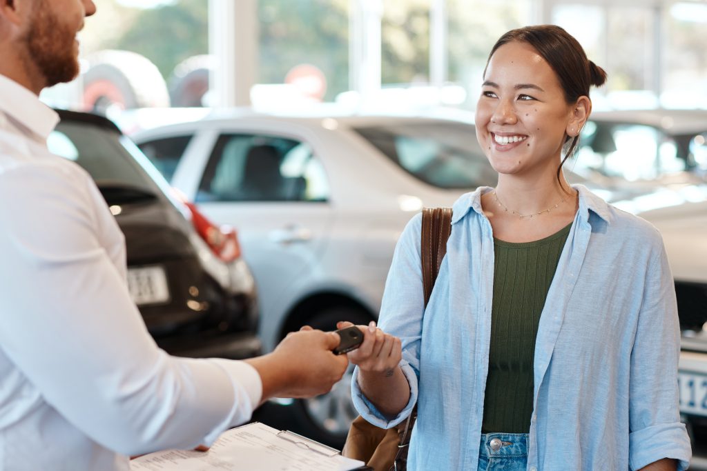 Mulher sorridente recebendo a chave do seu carro seminovo em uma concessionária, simbolizando confiança e segurança na compra.