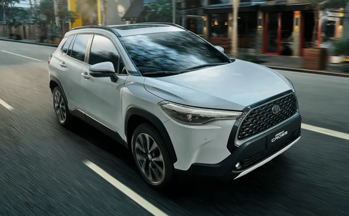 Toyota Corolla branco em movimento, registrado de perfil na estrada.