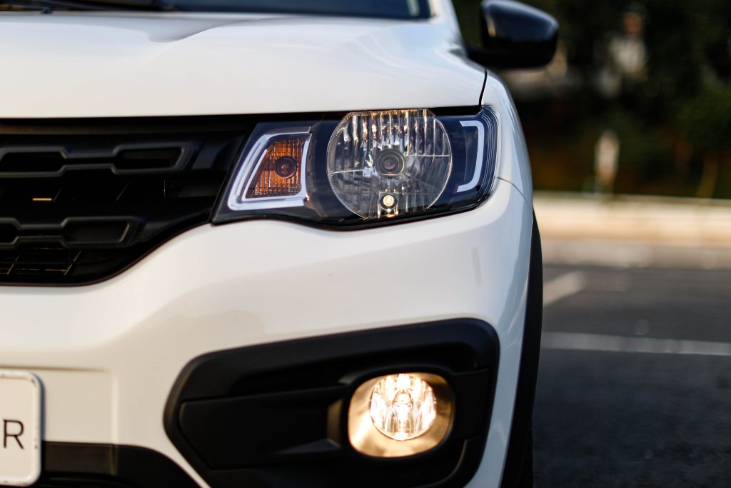 Detalhe do farol do Renault Kwid branco, evidenciando o design moderno e o estilo marcante do subcompacto.