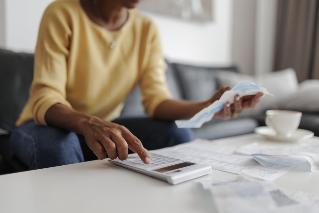 Pessoa segurando uma calculadora e analisando números em planilha para calcular parcelas de financiamento.