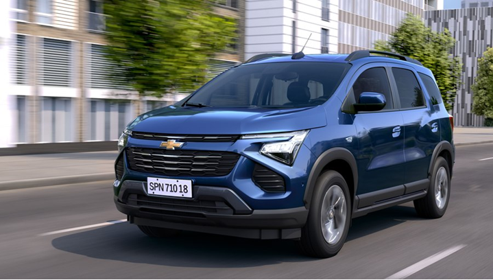Chevrolet Spin azul em movimento na estrada, destacando porte de minivan e design robusto em cenário rodoviário.